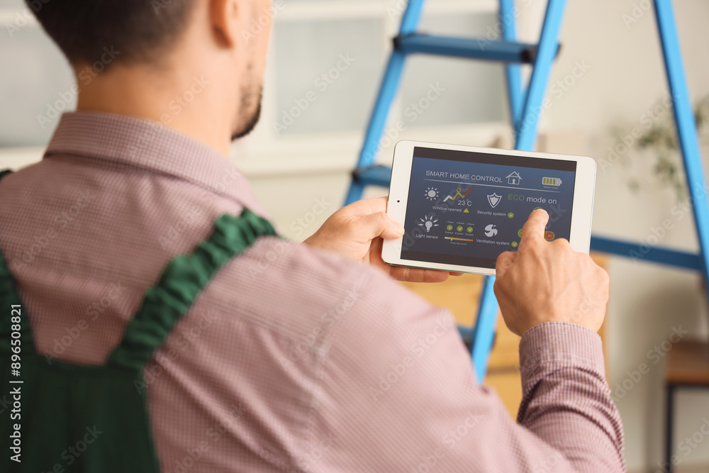 Male worker using tablet computer with installed alarm system in room, closeup Male worker using tablet computer with installed alarm system in room, closeup