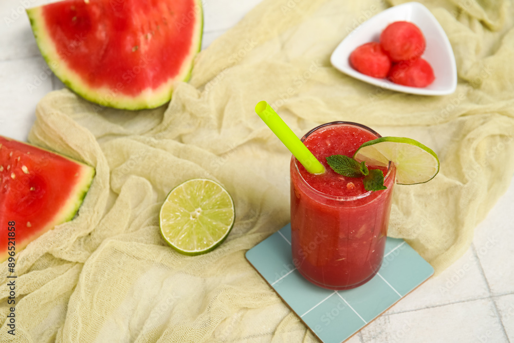 Glass of fresh watermelon juice with lime and mint on white tile table Glass of fresh watermelon juice with lime and mint on white tile table