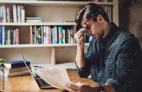 Documents, stress and man with laptop in home with struggle for job application online. Frustration, resume and person with computer for rejection email with cv vacancy for unemployment in apartment.