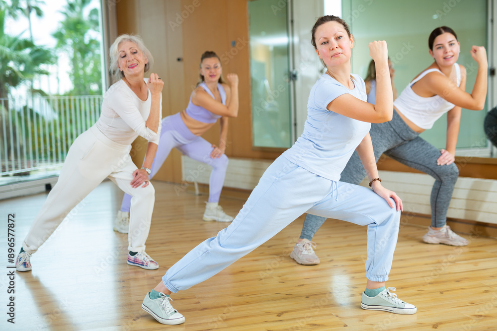 Obraz premium Active middle-aged woman practicing aerobic dance in training hall during fitness dance classes. Women training dance in hall