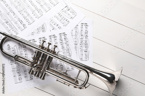 Trumpet and music sheet papers with notes on white wooden table, flat lay photo