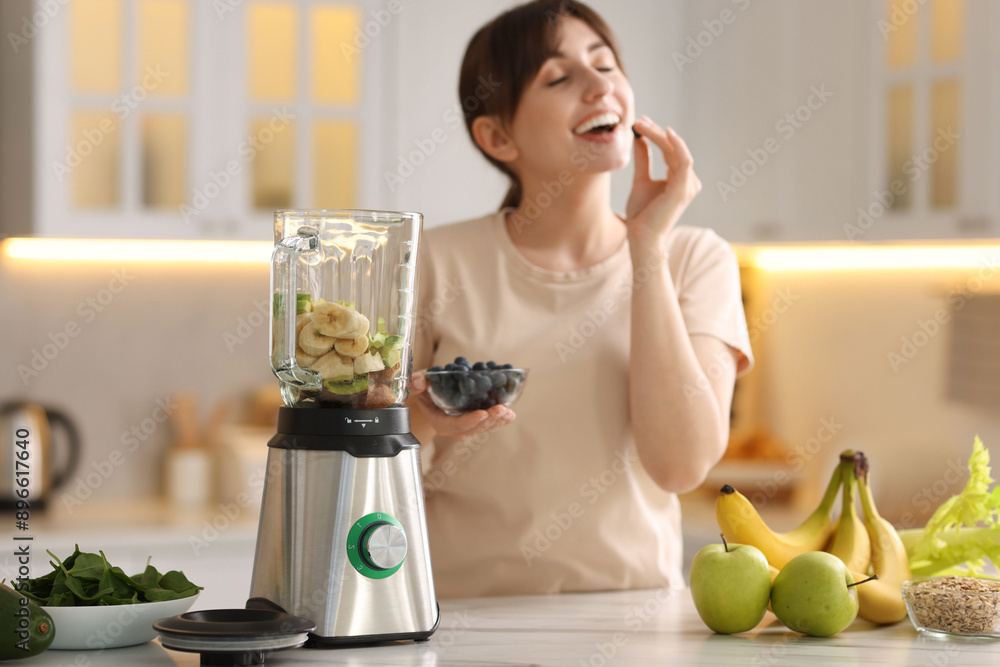 Young woman making delicious smoothie with blender at white marble table in kitchen Young woman making delicious smoothie with blender at white marble table in kitchen