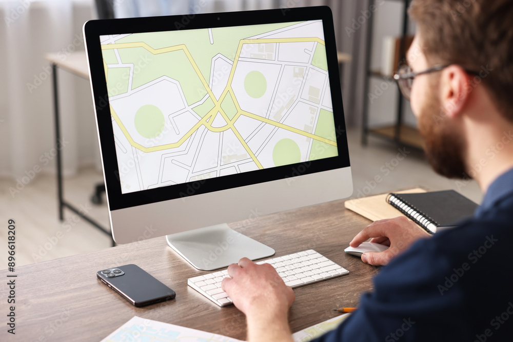 Cartographer working with cadastral map on computer at wooden table in office, closeup Cartographer working with cadastral map on computer at wooden table in office, closeup