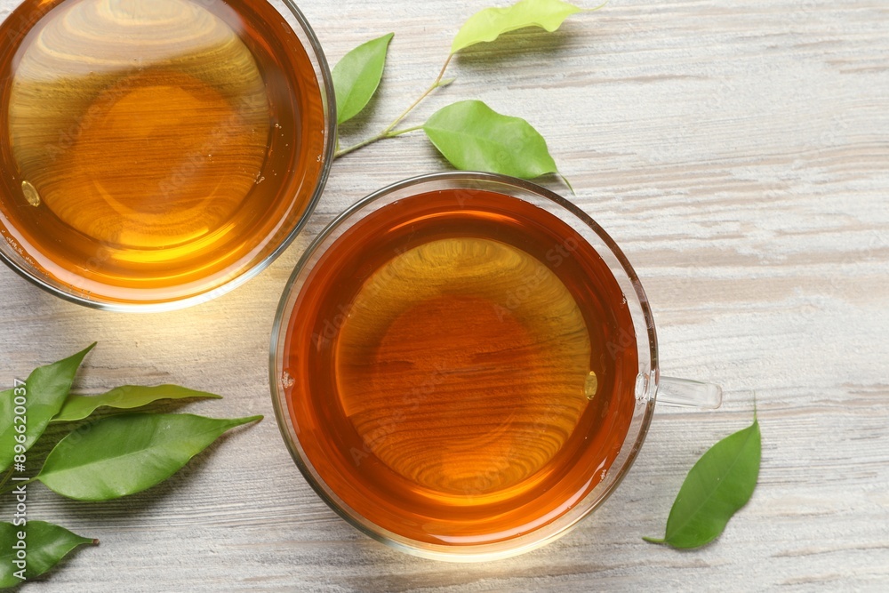 Refreshing green tea in cups and leaves on light wooden table, flat lay Refreshing green tea in cups and leaves on light wooden table, flat lay