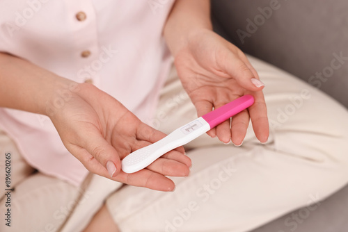 Young woman with pregnancy test on sofa at home, closeup