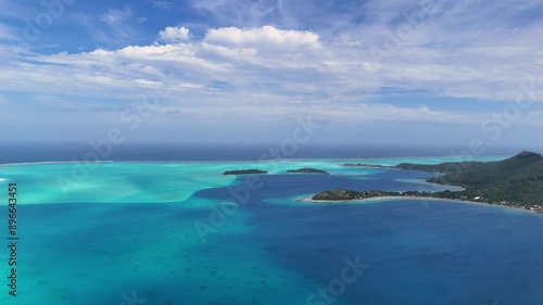 Aerial 360 degree panning footage by drone over Mount Otemanu on the island of Bora Bora. Beautiful azure and turquoise blue tropical ocean water surround the French Polynesia tourist destination. 