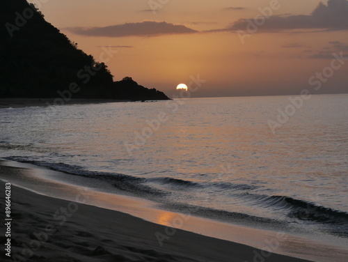 Sunset over Grande Anse beach in Deshaies, Guadeloupe. Evening by the sea and colorful romantic sky. Vacation landscape photo