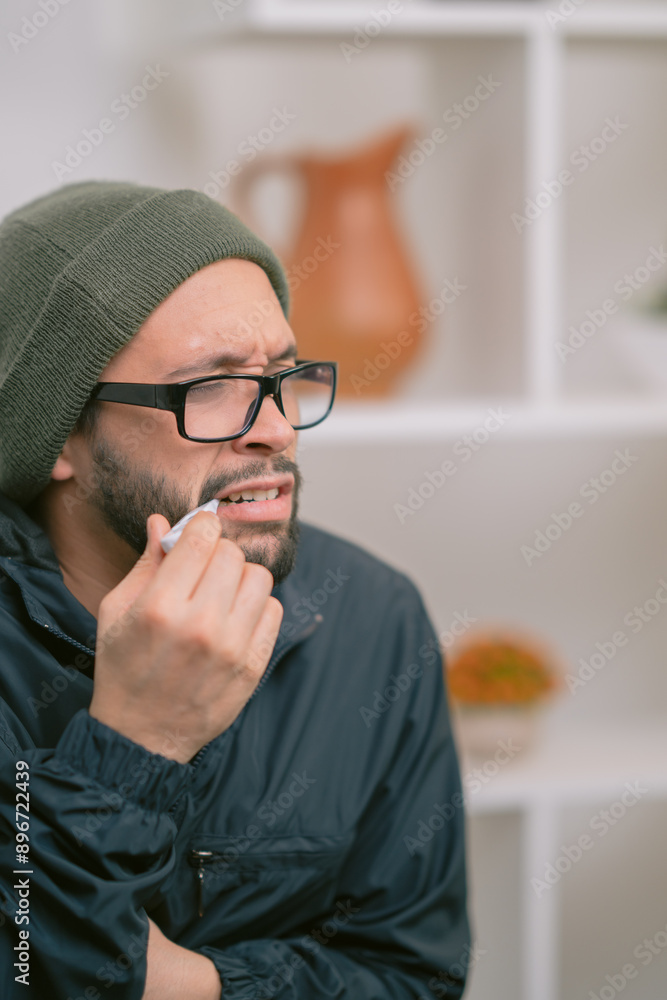 Sick man feeling unwell touching cheek with thermometer in mouth Sick man feeling unwell touching cheek with thermometer in mouth