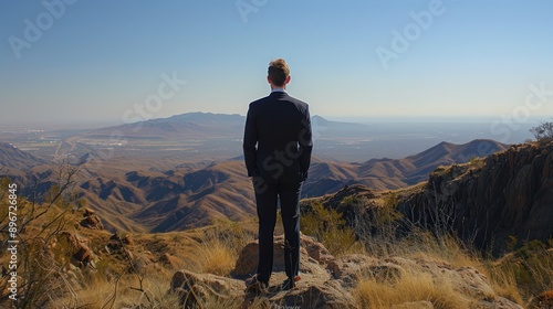 Successful businessman, a man in a suit, stands at the summit of the mountain, Panoramic view on mountains hills Successfully achieving your goal. Success Business Leadership, Winner on top. 