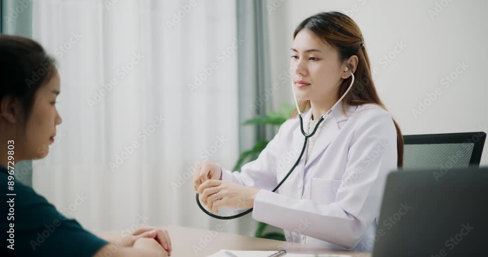 Handheld dolly shot, Asian doctor use stethoscope on chest of young female patient to check and listening her heartbeat in clinic office, Health and medicine consultant Handheld dolly shot, Asian doctor use stethoscope on chest of young female patient to check and listening her heartbeat in clinic office, Health and medicine consultant