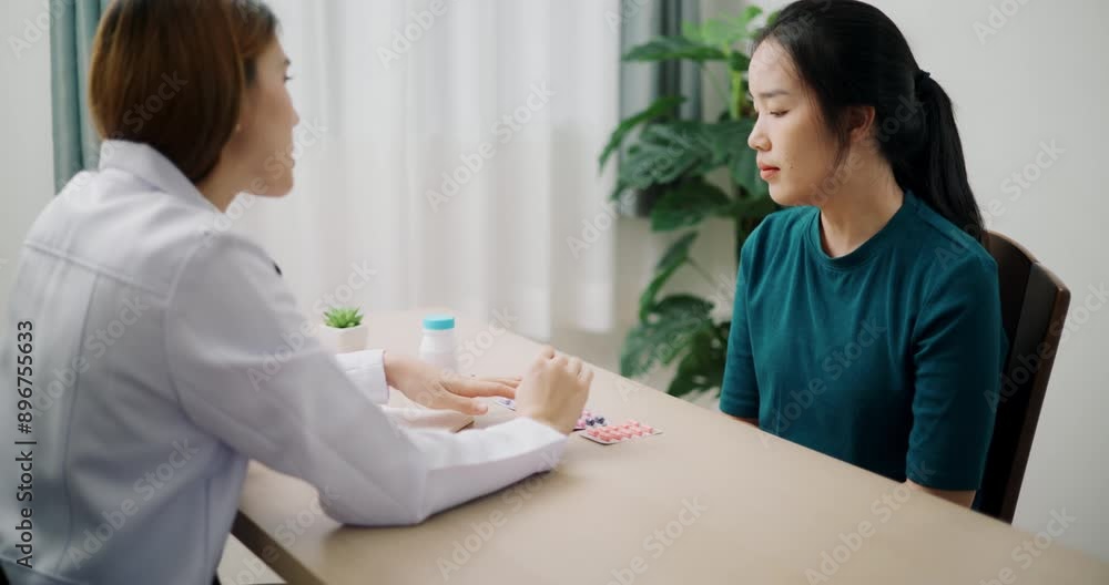 Handheld high angle view shot, Asian doctor explaining how to take medicine to young female patient in clinic office, Health and medicine consultant Handheld high angle view shot, Asian doctor explaining how to take medicine to young female patient in clinic office, Health and medicine consultant