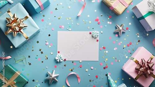 Festive flat lay with a blank card surrounded by colorful wrapped gifts, ribbons, and confetti on a blue background. Perfect for celebrations.