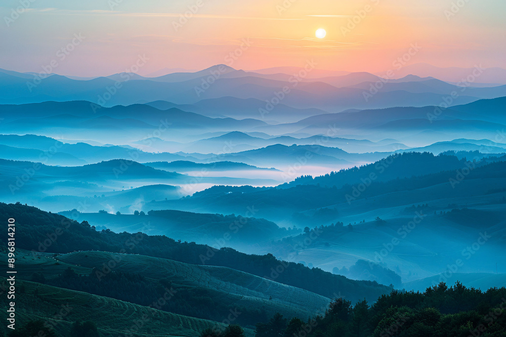 Fototapeta premium Misty morning mountains with fog enveloping the landscape under a soft sunrise