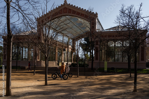 Dos jóvenes están manejando bicicleta en frente del Invernadero del Parque de la Ciutadella en Barcelona España.