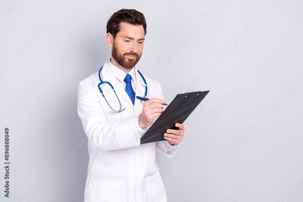Photo of handsome qualified doctor wear uniform hold paper holder writing diagnose isolated on grey color background Photo of handsome qualified doctor wear uniform hold paper holder writing diagnose isolated on grey color background