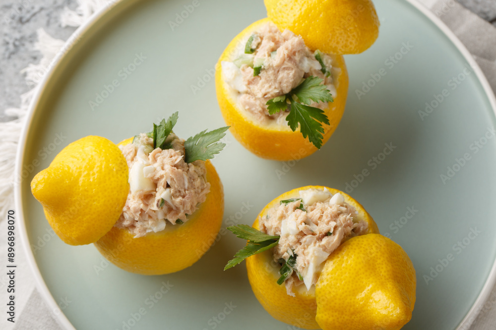 Snack in lemons. Salad of canned tuna, eggs, cucumber and cream close-up in a plate on the table. Horizontal top view from above Snack in lemons. Salad of canned tuna, eggs, cucumber and cream close-up in a plate on the table. Horizontal top view from above