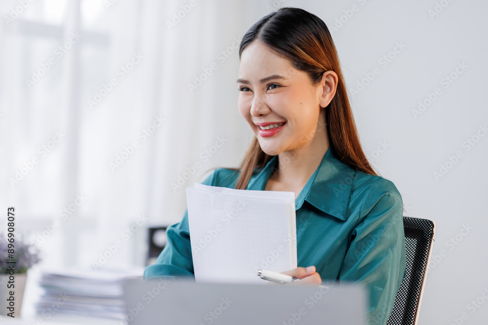 Asian woman in the workplace Work Hard writing notes on a pad from her laptop computer with analytical charts and graphs in front of her, business people concept Asian woman in the workplace Work Hard writing notes on a pad from her laptop computer with analytical charts and graphs in front of her, business people concept