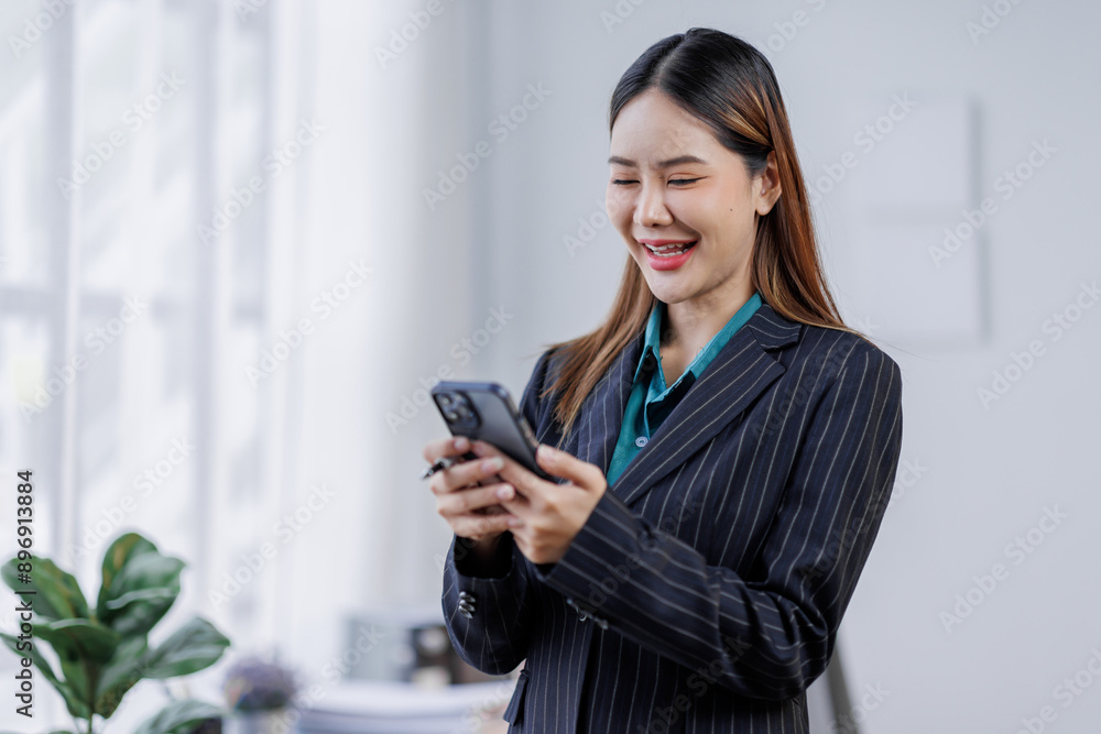 Young busy happy business asian woman employee, young female corporate executive holding digital phone standing at work. Young busy happy business asian woman employee, young female corporate executive holding digital phone standing at work.