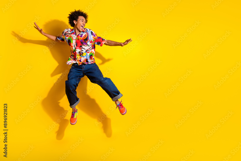 Full size photo of nice funky young man jump empty space wear shirt isolated on bright yellow color background Full size photo of nice funky young man jump empty space wear shirt isolated on bright yellow color background