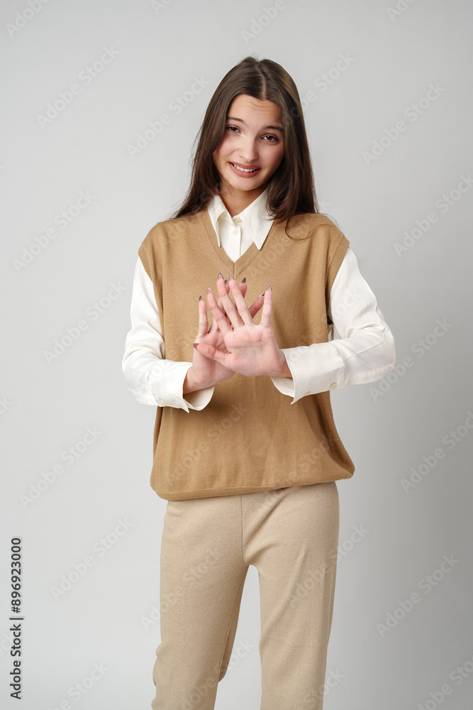 Young Woman Wearing a Brown Knit Vest and White Shirt Makes a Stop Gesture Young Woman Wearing a Brown Knit Vest and White Shirt Makes a Stop Gesture