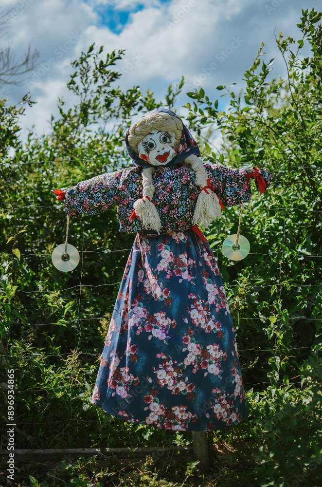 a bright scarecrow made of fabric in the garden to scare away animals such as birds a bright scarecrow made of fabric in the garden to scare away animals such as birds