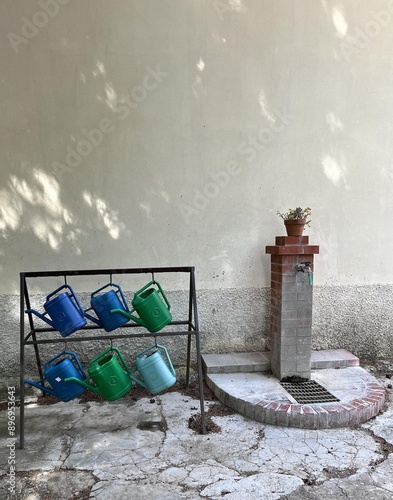 Hanging watering cans with a tap in the corner to fill and water the plants in the garden.