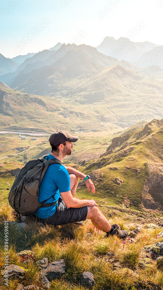 Naklejka premium Adventure in the Pyrenees: young hiker on the route to Espelunciecha Peak in the Pyrenees, with incredible views of the Ibón de Anayet and the majestic peaks of Anayet and Midi d'Ossau. 
