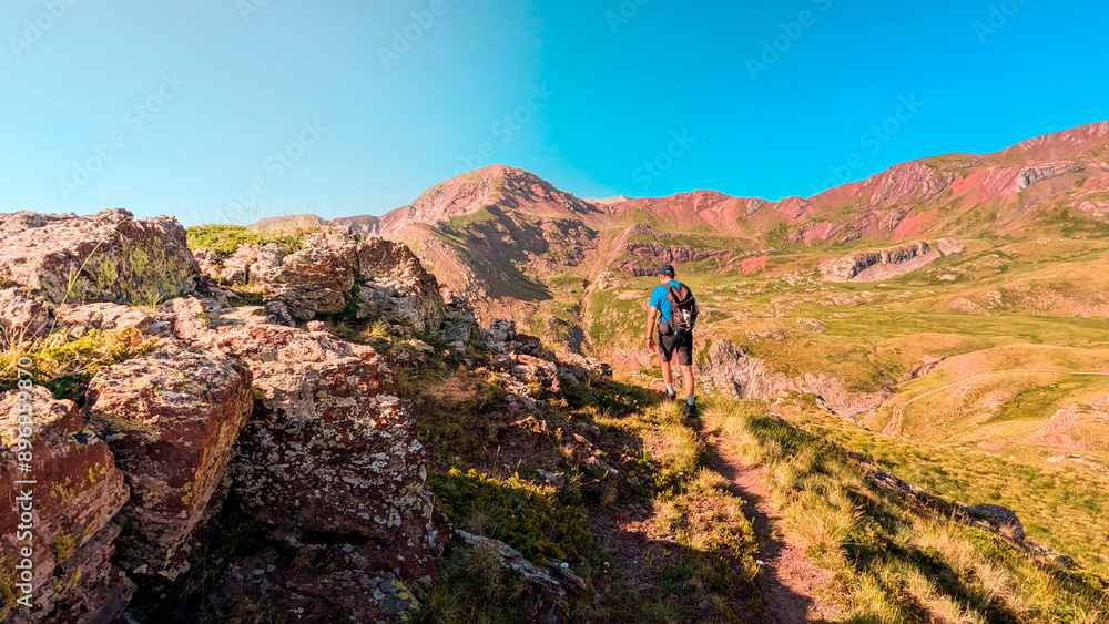 Fototapeta premium Discovering the Pyrenees: young man ascending Arroyetas Peak, surrounded by the beauty of the Ibón de Anayet, Anayet Peak and the majestic Midi d'Ossau 