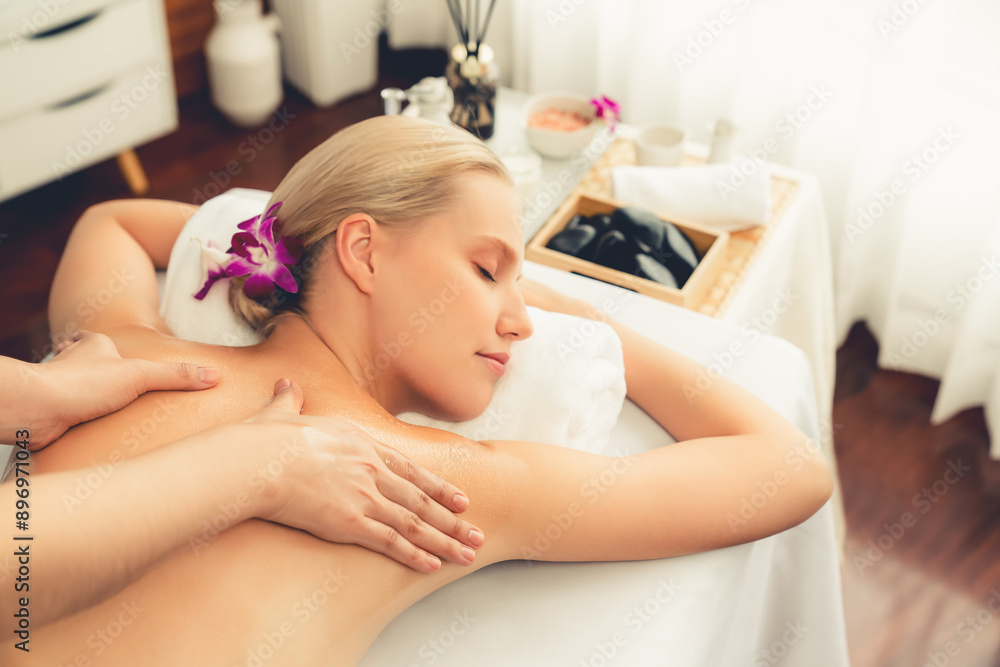 Caucasian woman customer enjoying relaxing anti-stress spa massage and pampering with beauty skin recreation leisure in day light ambient salon spa at luxury resort or hotel. Quiescent Caucasian woman customer enjoying relaxing anti-stress spa massage and pampering with beauty skin recreation leisure in day light ambient salon spa at luxury resort or hotel. Quiescent