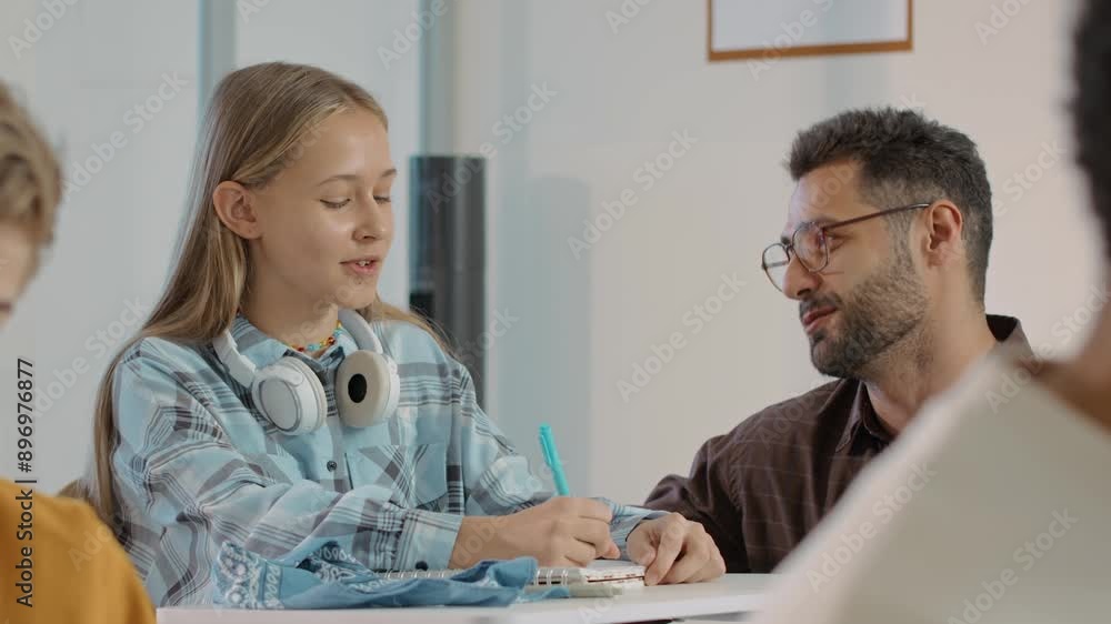 Medium shot of young male teacher wearing glasses cheering up and motivating teenage Caucasian girl having difficulties with accomlishment of task Medium shot of young male teacher wearing glasses cheering up and motivating teenage Caucasian girl having difficulties with accomlishment of task