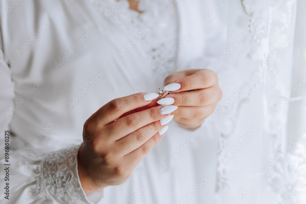 A woman is holding a ring in her hand. The ring is white and has a diamond on it. The woman is wearing a white gown and has her hands clasped together. Concept of elegance and sophistication A woman is holding a ring in her hand. The ring is white and has a diamond on it. The woman is wearing a white gown and has her hands clasped together. Concept of elegance and sophistication