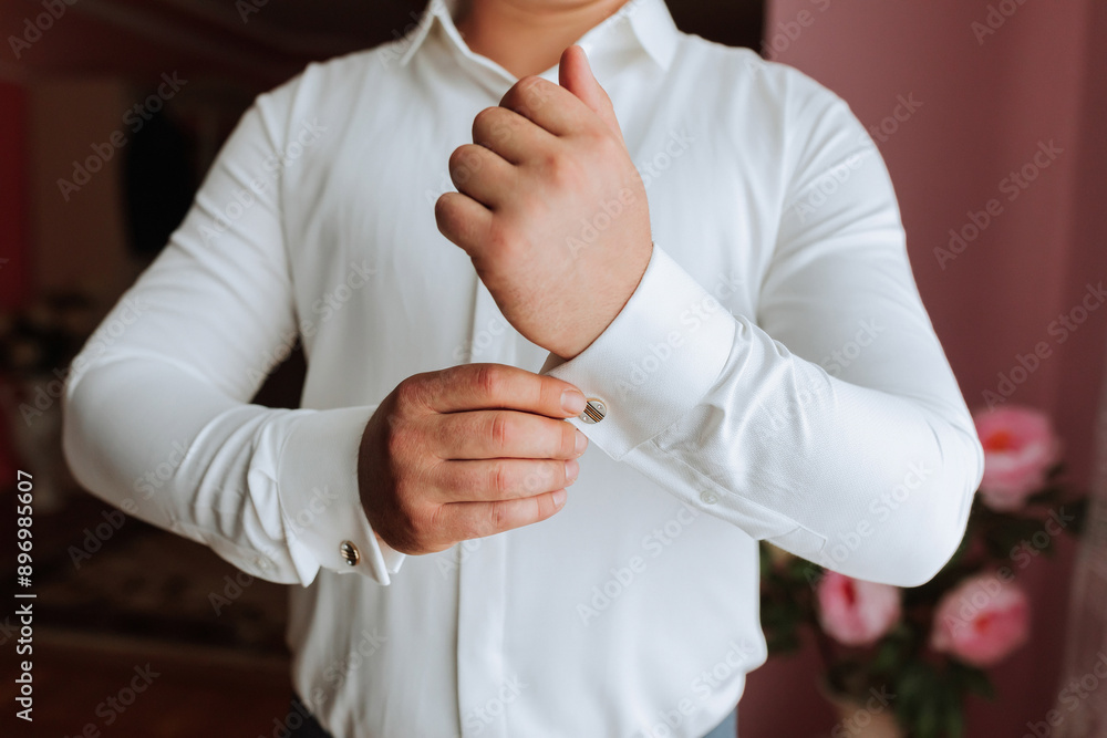 A man in a white shirt is getting dressed and adjusting his cuff. Concept of formality and attention to detail, as the man carefully straightens his shirt and cuff A man in a white shirt is getting dressed and adjusting his cuff. Concept of formality and attention to detail, as the man carefully straightens his shirt and cuff