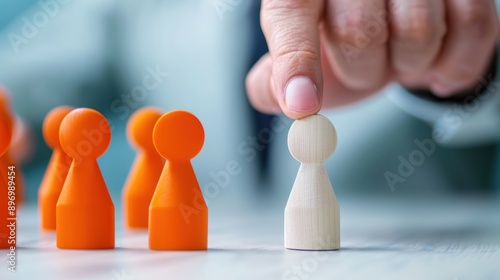 Close-up of a hand picking an orange pawn from a group of white pawns, representing selection and leadership.