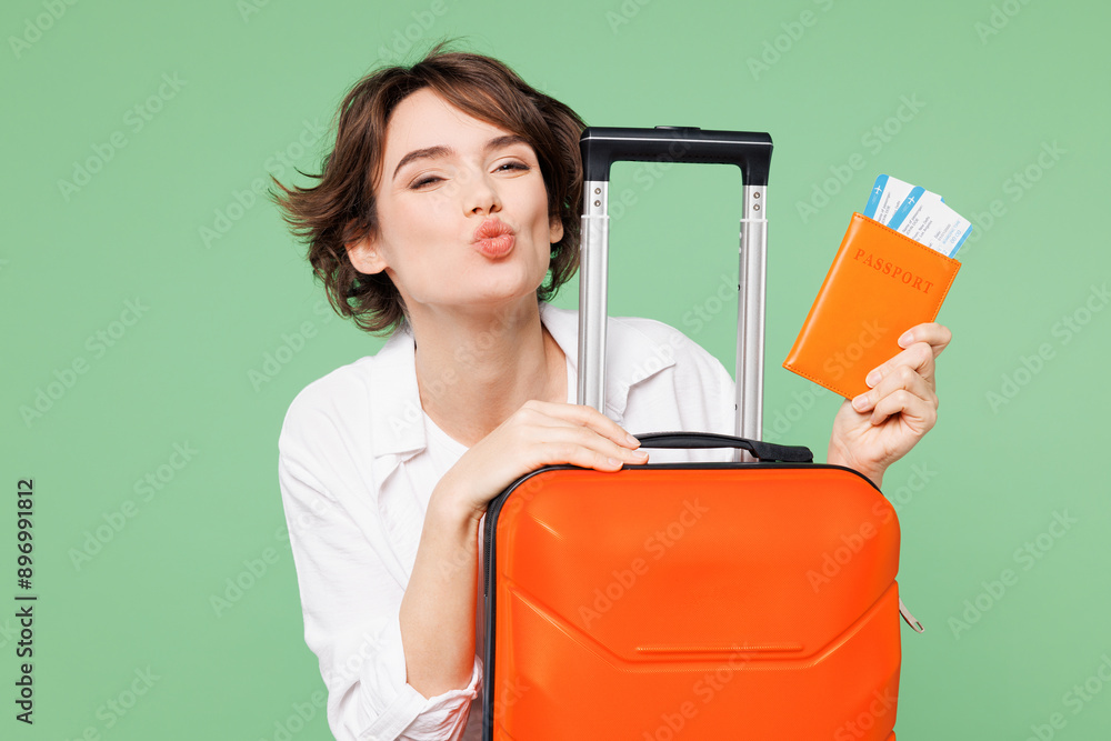 Close up traveler woman wears casual clothes hold passport ticket bag look camera pov kiss isolated on plain green background. Tourist travel abroad in free time rest getaway. Air flight trip concept. Close up traveler woman wears casual clothes hold passport ticket bag look camera pov kiss isolated on plain green background. Tourist travel abroad in free time rest getaway. Air flight trip concept.