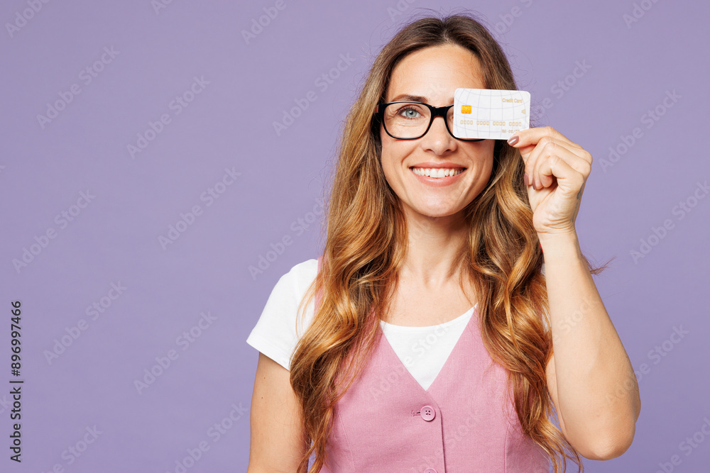 © ViDi Studio - Young successful employee business woman corporate lawyer wear classic suit vest white t-shirt glasses work in office hold cover eye with credit bank card isolated on plain pastel purple background.
