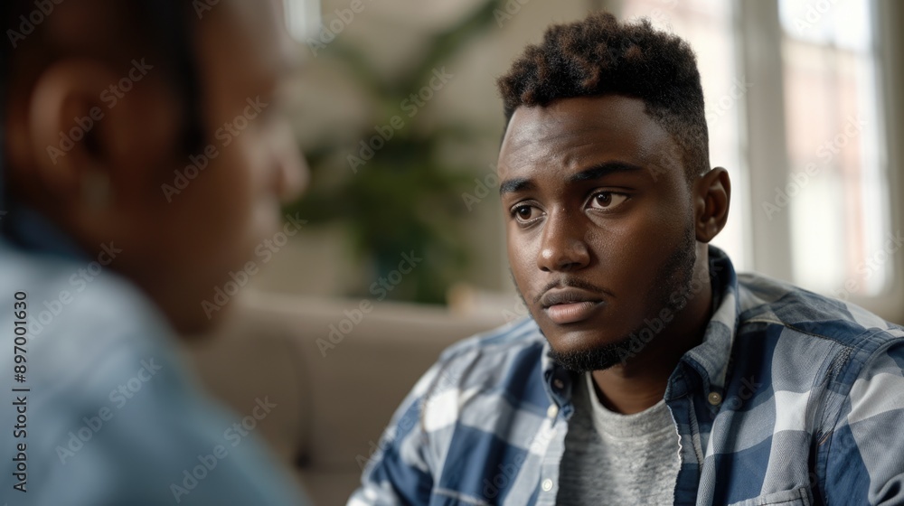Two people seated, engaged in conversation. Focus on younger male's expression of concern or seriousness. Two people seated, engaged in conversation. Focus on younger male's expression of concern or seriousness.