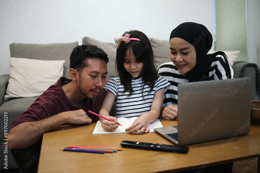Asian Young Mother And Father Teaching Little Daughter Making Homework At Home Asian Young Mother And Father Teaching Little Daughter Making Homework At Home