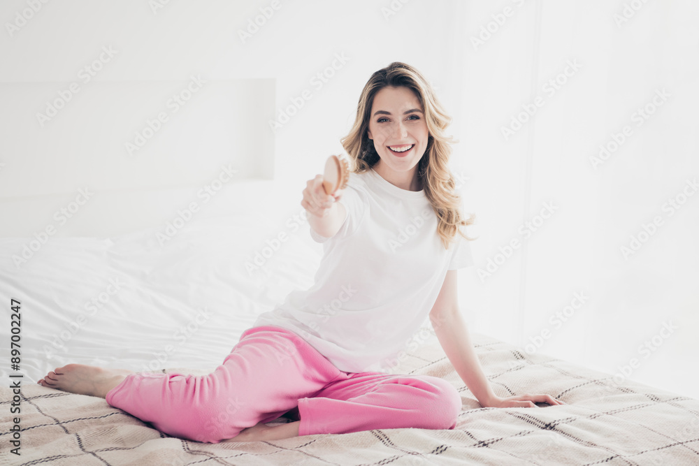 Photo of positive girl sit bed point hair brush in day light room Photo of positive girl sit bed point hair brush in day light room
