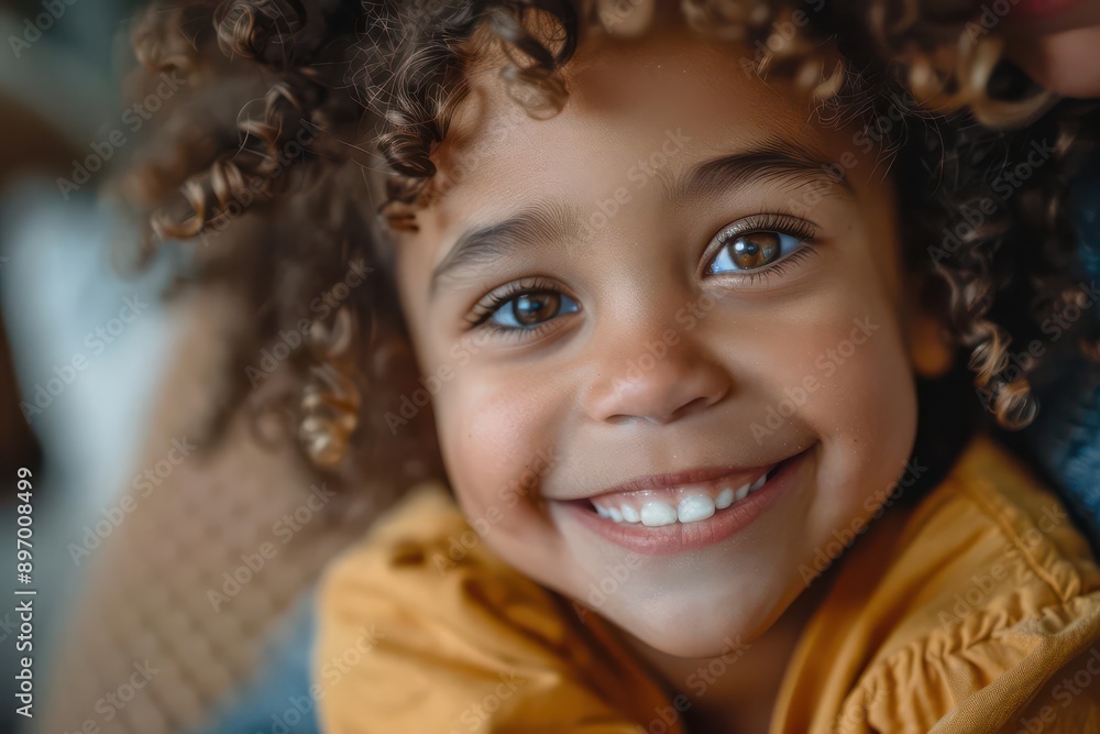 A young child with curly hair smiles brightly at the camera. Their eyes sparkle with joy and their teeth shine white. A young child with curly hair smiles brightly at the camera. Their eyes sparkle with joy and their teeth shine white.