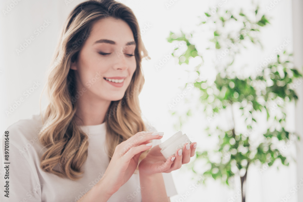 Photo of positive girl using cream jar lotion applying in day light room indoors Photo of positive girl using cream jar lotion applying in day light room indoors