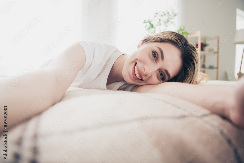 Photo of positive smiling girl lying enjoy make selfie video in day light room Photo of positive smiling girl lying enjoy make selfie video in day light room