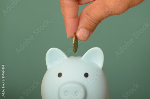 The image of a hand holding money to place in a piggy bank symbolizes the act of saving and financial responsibility. photo