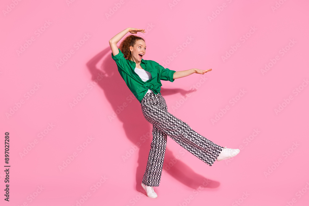 Full length photo of cheerful pretty lady dressed green shirt having fun empty space isolated pink color background Full length photo of cheerful pretty lady dressed green shirt having fun empty space isolated pink color background