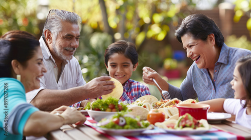 mexican family eating tasty homemade tacos in the garden of their house. all happy.