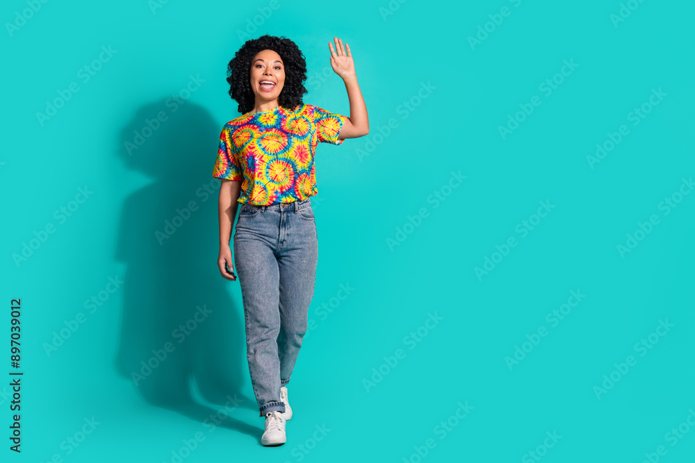 Full length photo of shiny attractive lady dressed retro t-shirt walking waving arm empty space isolated blue color background Full length photo of shiny attractive lady dressed retro t-shirt walking waving arm empty space isolated blue color background