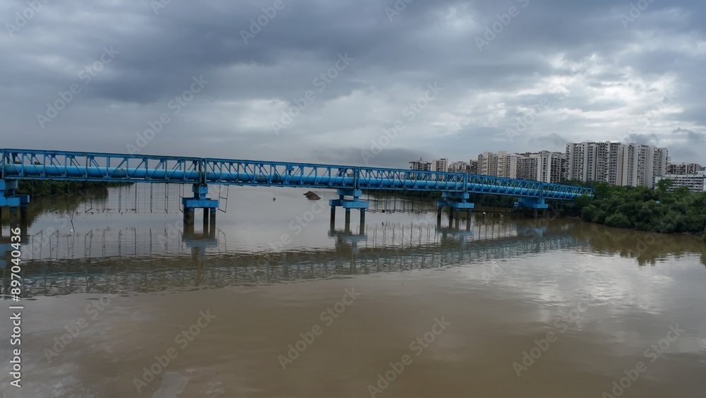 A blue-colored pipeline bridge over a river, with water beneath and a cloudy sky, emphasizing its architectural structure.
A blue-colored pipeline bridge over a river, with water beneath and a cloudy sky, emphasizing its architectural structure.