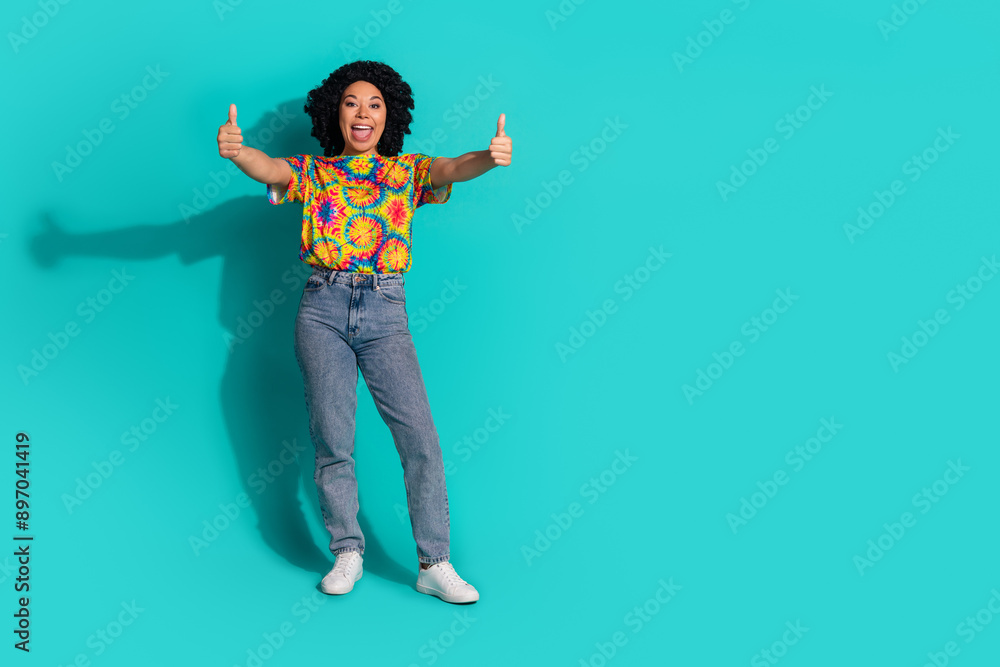 Photo of adorable pretty nice woman wear trendy print clothes demonstrate thumb up empty space isolated on cyan color background Photo of adorable pretty nice woman wear trendy print clothes demonstrate thumb up empty space isolated on cyan color background