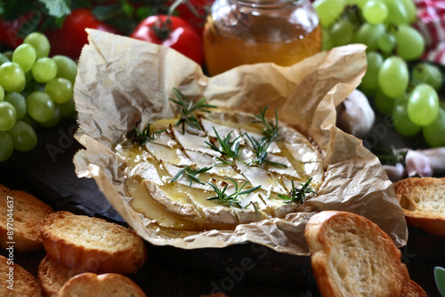 Baked camembert cheese with rosemary, garlic and honey on baking paper