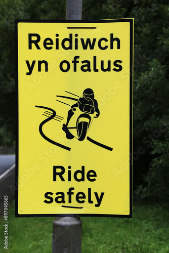 A bright yellow, bilingual sign reminding mortorbike riders to travel safely whilst touring Wales, UK. photo