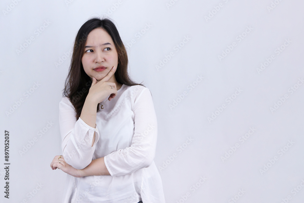 Unsure hesitant worried Asian woman looking away and touching chin, face tough decision, weighing all pros and cons, trying to come up with solution Unsure hesitant worried Asian woman looking away and touching chin, face tough decision, weighing all pros and cons, trying to come up with solution